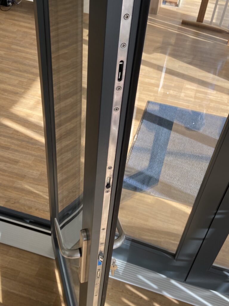 aluminium bi fold doors with locking mechanism and handle detail finished in anthracite grey bifold doors trinity windows jersey 2500