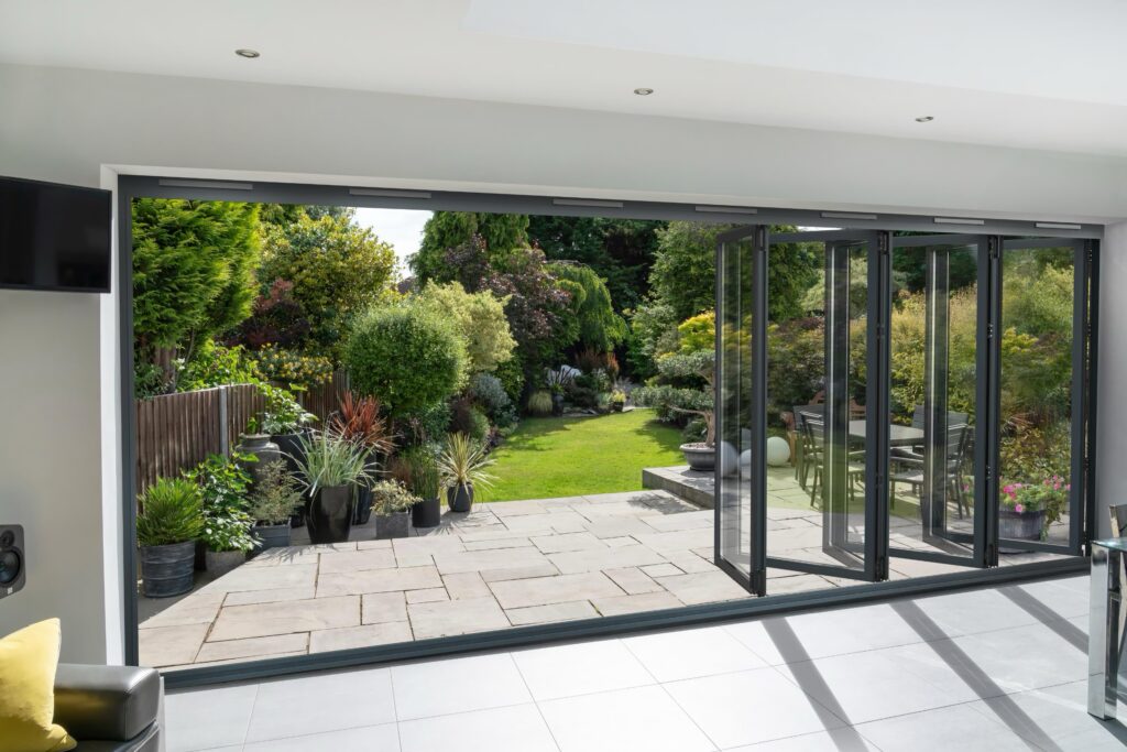 technal floating mullion bifold door grey aluminium half open garden view bifold doors trinity windows jersey 2500
